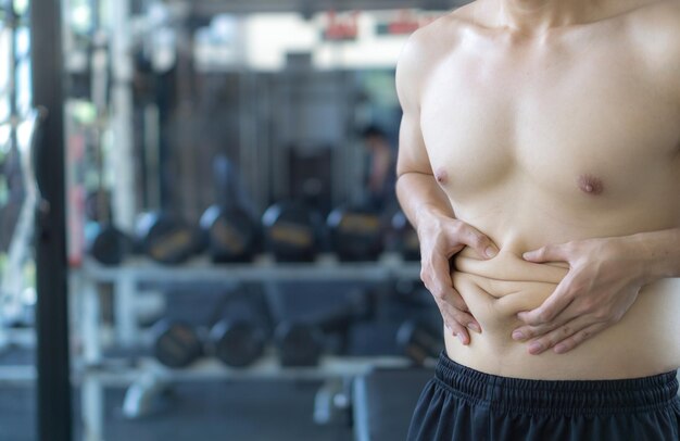 Photo midsection of overweight man holding abdomen in gym
