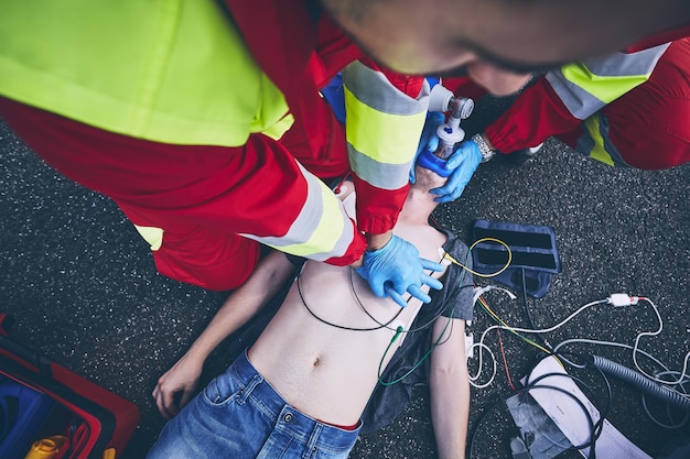 Midsection of paramedic giving cpr to unconscious man lying on street