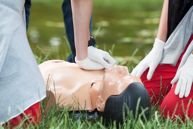 Photo midsection of paramedic practicing cpr on male dummy at field