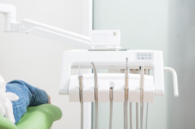 Midsection of patient sitting on seat by medical equipment in clinic