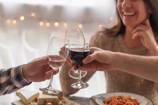 Foto sezione centrale di persone che brindano allo champagne e mangiano a casa