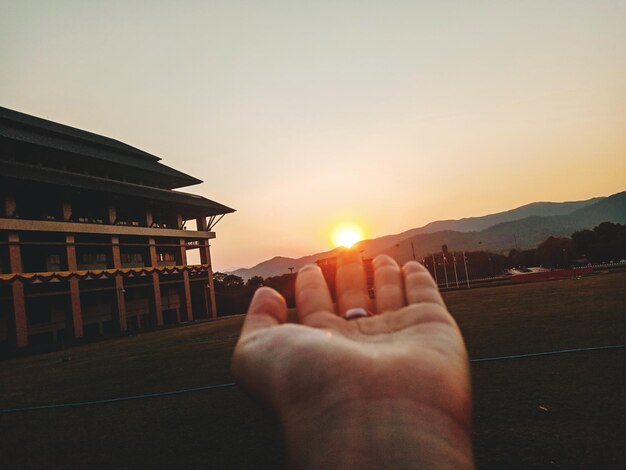 Midsection of person against sun during sunset