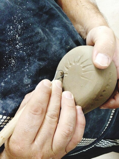 Photo midsection of person engraving on clay at workshop