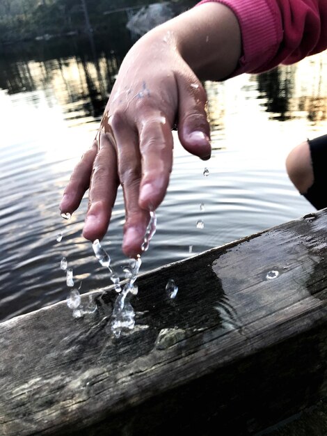 Foto sezione centrale della mano di una persona con l'acqua nel lago