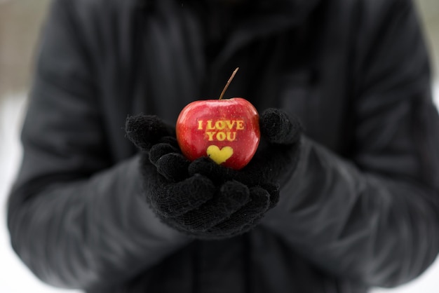 Foto sezione centrale di una persona che tiene una mela con testo e forma di cuore