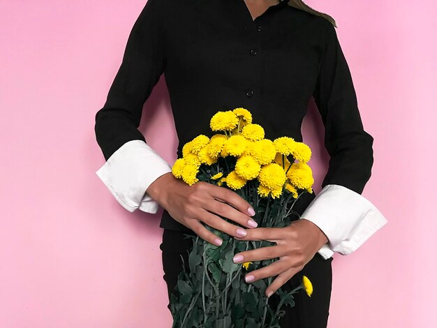 Midsection of person holding bouquet against orange wall