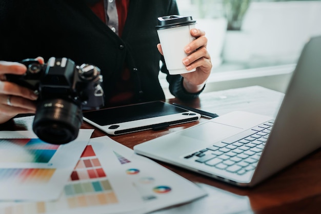 Photo midsection of person holding camera and disposable cup on table