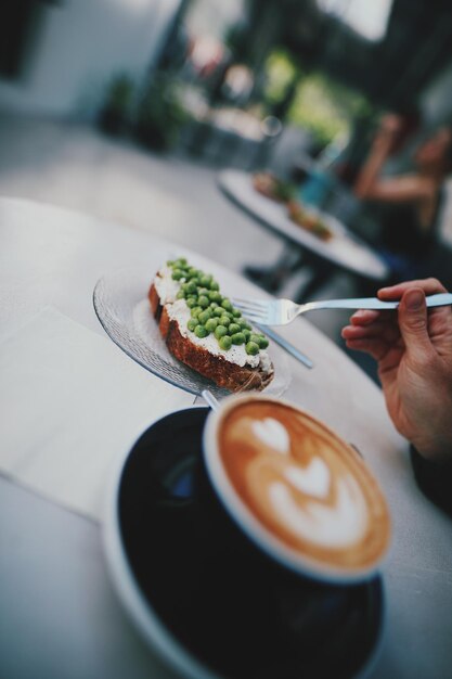 Foto sezione centrale di una persona che tiene una tazza di caffè sul tavolo