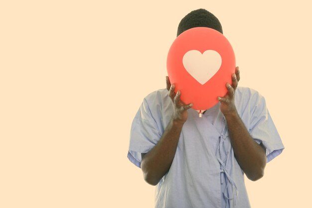 Midsection of person holding heart shape against wall