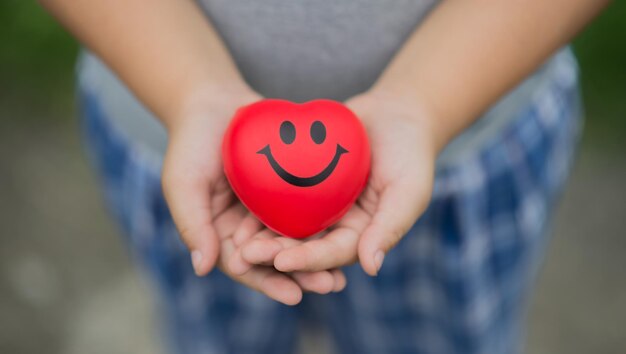 Photo midsection of person holding heart shape while standing outdoors