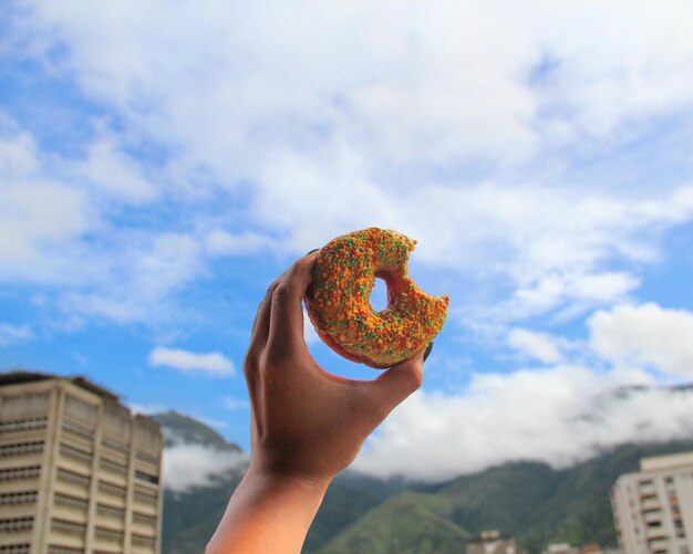 Midsection of person holding ice cream against sky