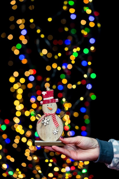 Foto sezione centrale di una persona che tiene in mano un albero di natale illuminato di notte