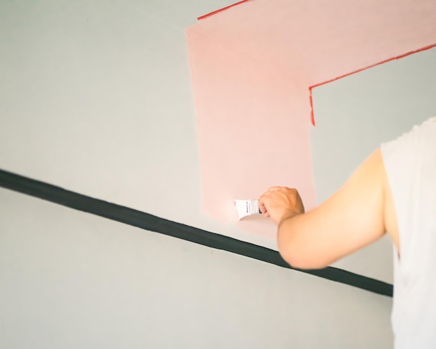 Midsection of person holding paper against wall