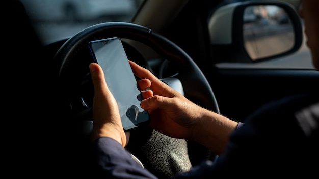 車の中でスマートフォンを握っている人のミッドセクション