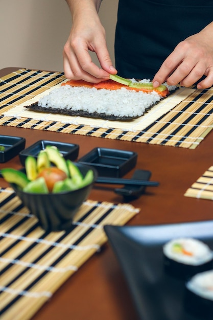 Foto sezione centrale di una persona che tiene il sushi sul tavolo