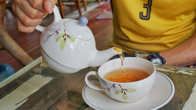 Foto sezione centrale di una persona che tiene una tazza di tè sul tavolo