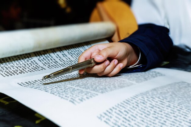 Midsection of person pointing at old traditional scroll on table