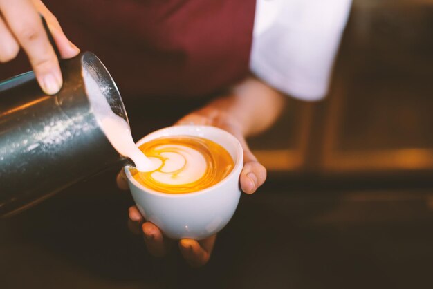 Photo midsection of person pouring foam into coffee cup