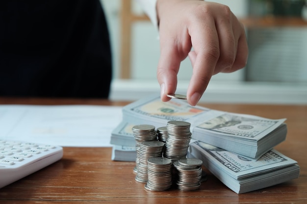 Midsection of person stacking coins by paper currency on office desk