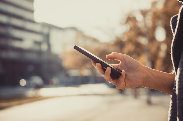 midsection of person using mobile phone outdoors