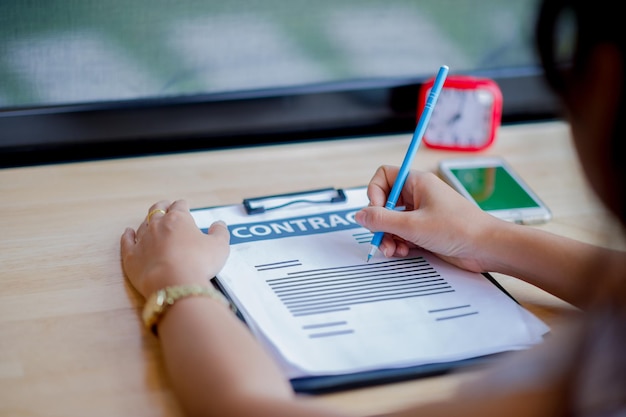 Photo midsection of person with pen and contract paper at desk