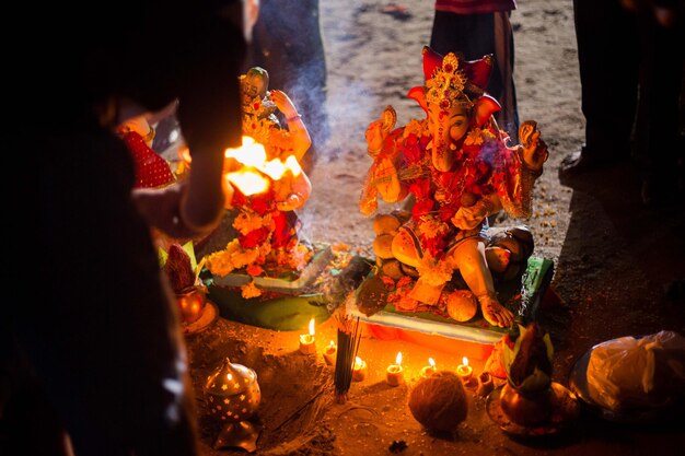 Photo midsection of person worshipping to ganesha at night