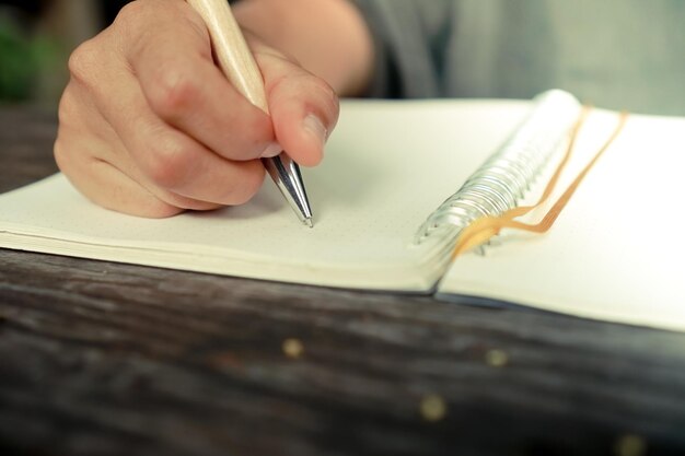 Foto sezione centrale di una persona che scrive su un libro al tavolo