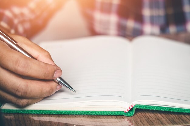 Midsection of person writing in diary at desk