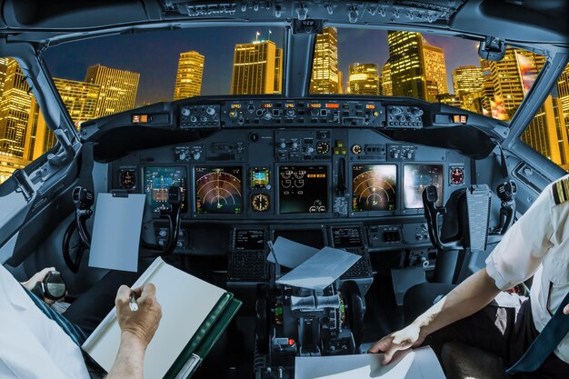 Photo midsection of pilots holding paper in cockpit over cityscape