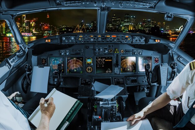 Foto sezione centrale di piloti che tengono la carta nella cabina di pilotaggio sopra il paesaggio cittadino