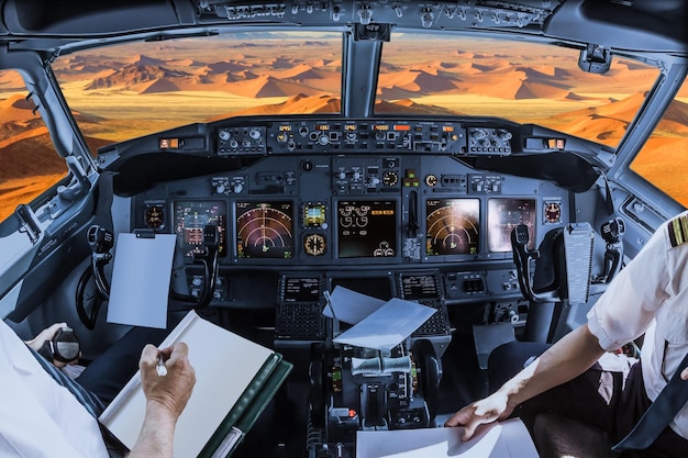 Foto sezione centrale di piloti che tengono la carta nella cabina di pilotaggio sopra il deserto