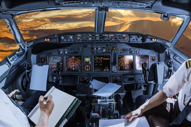 Foto sezione centrale di piloti che tengono la carta nella cabina di pilotaggio sopra il deserto