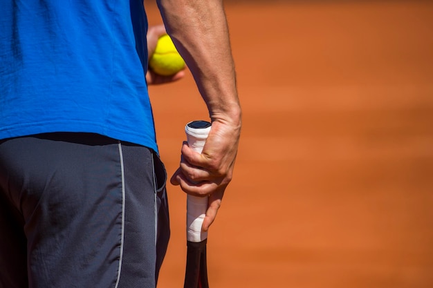 Photo midsection of player with ball and tennis racket on court