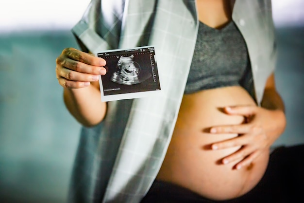 midsection portrait of unrecognizable woman during last months of pregnancy holding her big belly