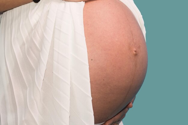 Foto sezione centrale di una donna incinta sullo sfondo blu