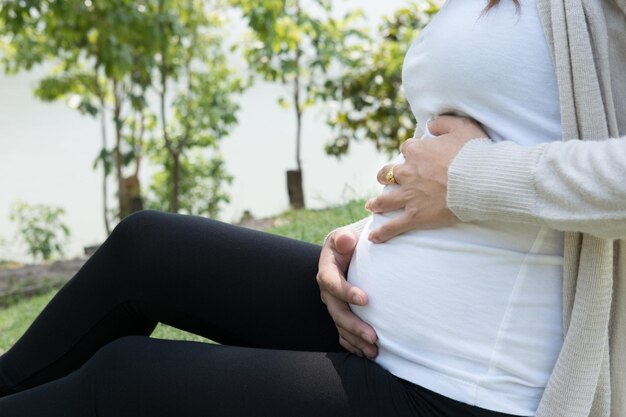 Midsection of pregnant woman siting on land