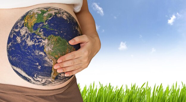 Photo midsection of pregnant woman with planet earth on stomach against sky