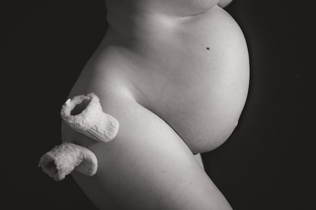 Photo midsection of pregnant woman with socks over black background