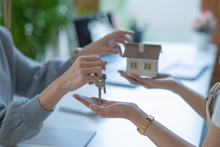 Photo midsection of real estate agent giving house key to customer while sitting in office