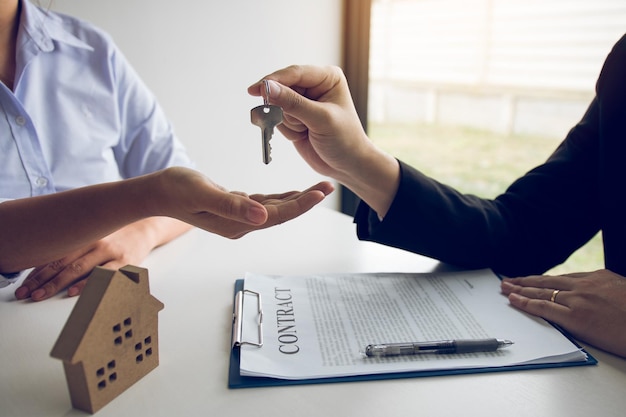 Средний раздел агента по недвижимости, дающего ключ клиенту на столе.