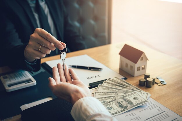 テーブルの上で顧客に鍵を渡す不動産エージェントのミッドセクション