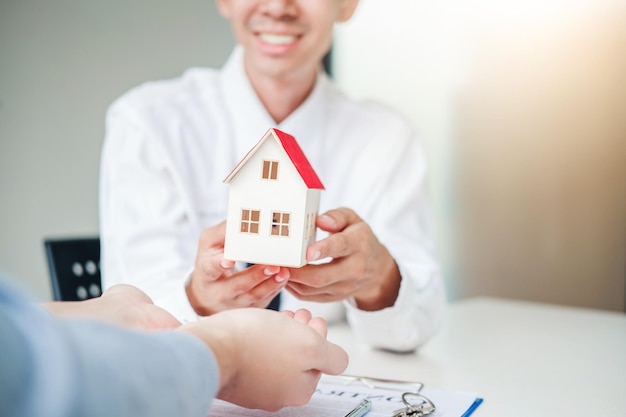 Foto sezione centrale dell'agente immobiliare che dà la casa modello al cliente in ufficio