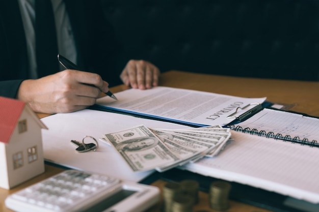 midsection of realtor signing contract at desk
