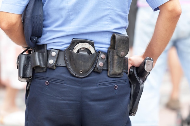 Foto midsection vista posteriore di un poliziotto con cintura con manette e pistola