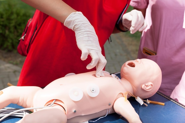 Photo midsection of rescue worker performing cpr on baby mannequin