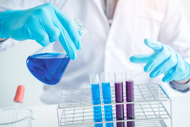 Midsection of scientist mixing liquid in laboratory