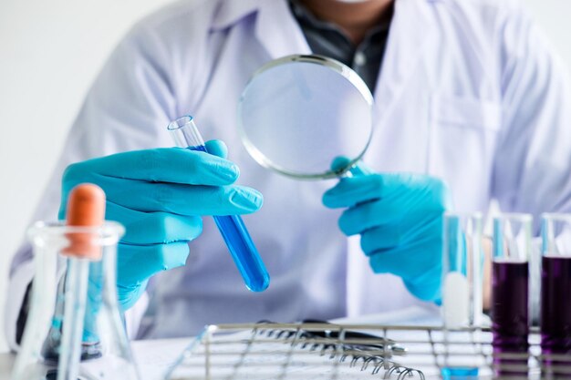 Photo midsection of scientist using magnifying glass on table