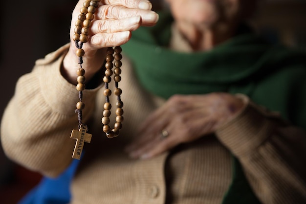 Photo midsection of senior woman holding wooden rosary beads with cross