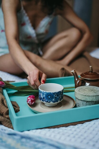 Foto sezione centrale di una donna sensuale che tiene un drink seduta sul tavolo