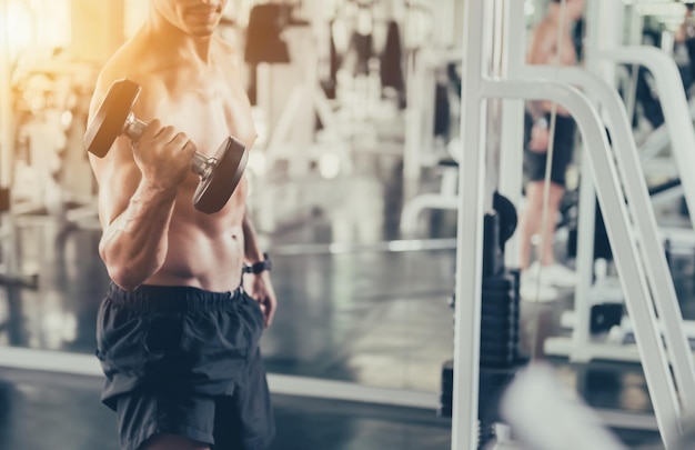 Photo midsection of shirtless man lifting dumbbell in gym